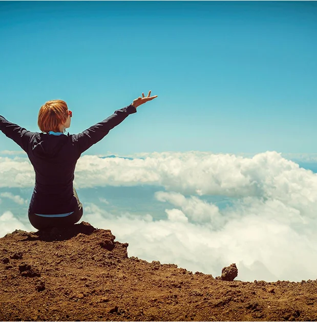 truma-therapy5 Person with outstretched arms on a mountaintop, looking out over clouds.
